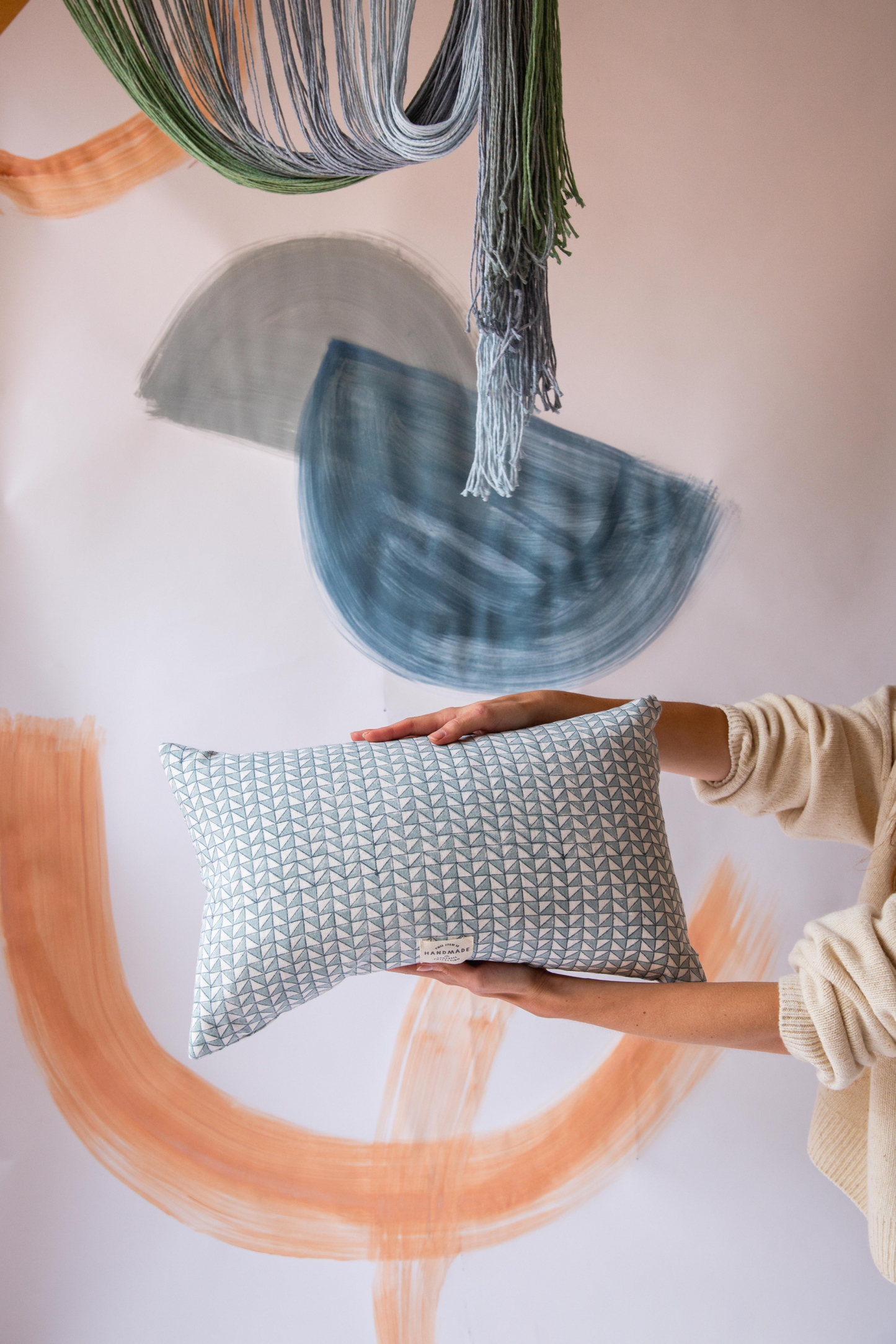 Someone holding a blue rectangular cushion with a triangle pattern on